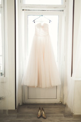 Fashion wedding dress for bride hanging near window