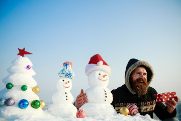 Man smiling with snowmen and snowy xmas tree