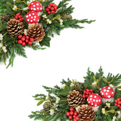 Christmas fantasy decorative border with fly agaric mushroom ornaments, holly, pine cones, mistletoe, cedar cypress and juniper leaf sprigs and ivy on white background.