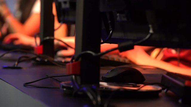 A lot of teenagers playing on computer games. Close-up of hands with keyboards and mouses.