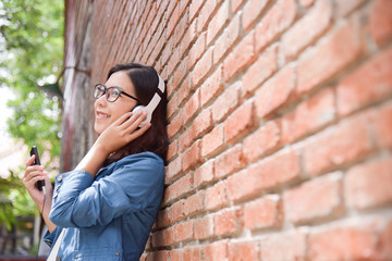 Woman in blue shirt listening to the music with headphone.