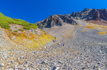 stone slope of the volcano with walking tourists.