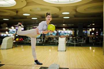 Girl with bowling ball on alley played at bowling club.