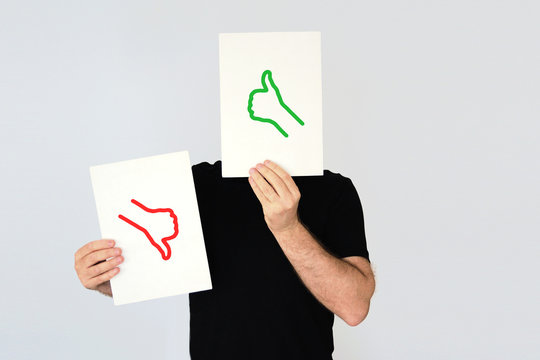 Man holding the  thumbs up and thumbs down icons. Social media and costumer feedback concept. Empty copy space for Editor's text.