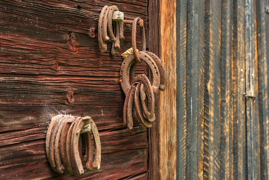 Rusty old horseshoes hanging on barn wall.
