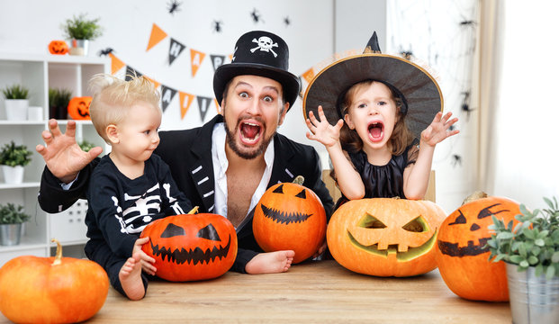 family father and children in costumes   to halloween with pumpkin
