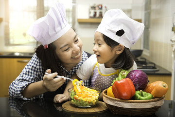 Asian mother teaching daughter making salad in kitchen,Cooking concept