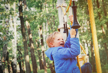 happy little boy climbing on outdoor playground