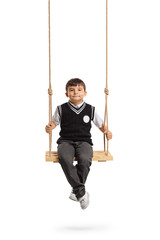 Small schoolboy seated on a wooden swing