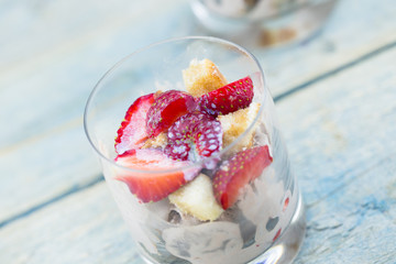 Sweet dessert from cheese and yogurt with fresh ripe strawberry in a glass jar, on rustic wooden background. Selective focus