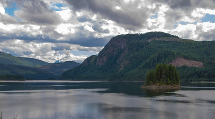 Fototapeta premium Snow capped peak in the distance against a still lake.