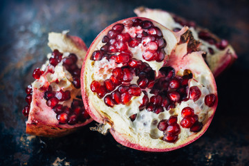 Half of pomegranate fruit on black rustic background.