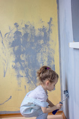 Naklejka premium Little kid girl paints wall by paint roller