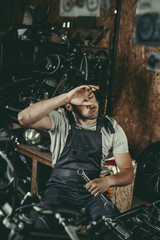 Fototapeta na wymiar tired mechanic repairing motorbike