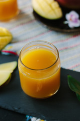 Orange and mango fruit juice over black slate.