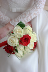 Bride in white wedding dress sitting and holding wedding bouquet