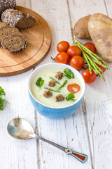 Beautiful asparagus cream soup with toasted bread on white wooden table.