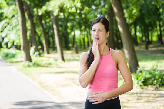 sporty woman toothache in a park
