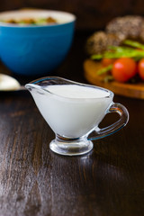 Natural cream dip in a glass bowl on dark wooden board.