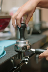 Barista pulling coffee at metal holder for espresso making.