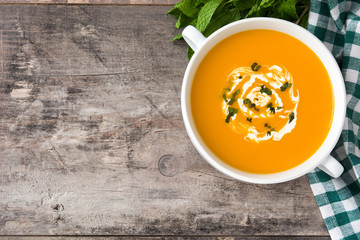 Pumpkin soup in white bowl on wooden table