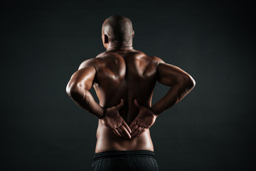 Fototapeta na wymiar Back view of young african sports man feeling pain in his back