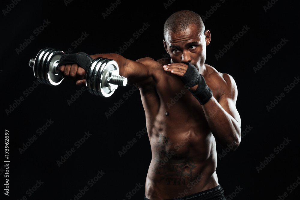 Wall mural Afroamerican sports man posing like a fight with dumbbells