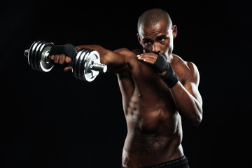 Fototapeta na wymiar Afroamerican sports man posing like a fight with dumbbells
