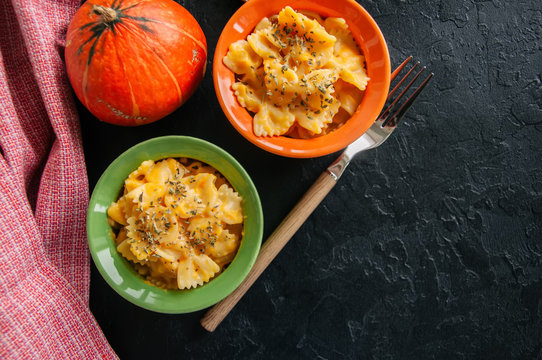 Pumpkin creamy mac and cheese baked pasta over black stone background. Comfort food.