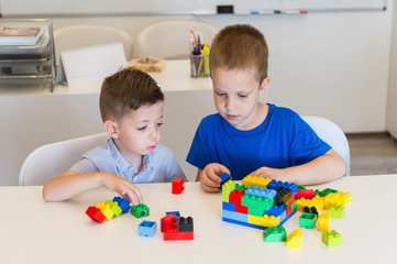 two child boy playing with cubes on the table