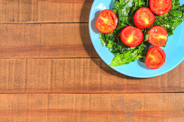 Tomatoes and greens spinach on a blue plate
