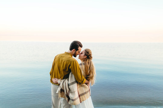 A beautiful couple is embracing on the sea background. Moment before the kiss. Romantic date on the beach. View from the back. Wedding. Artwork