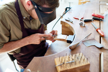 High angle portrait of jeweler making ring in workshop, forming and polishing it with tools