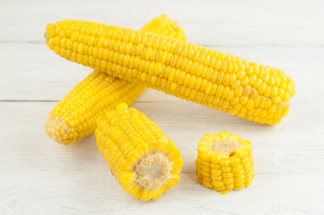 Boiled yellow ripe whole corn and slices of corn on old rural white wooden planks
