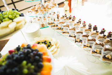 Delicious and tasty dessert table with cupcakes shots at reception closeup