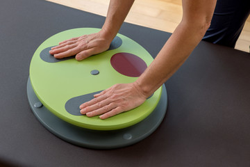 Hände auf Wackelbrett Gleichgewichtstraining in der Physiotherapie Praxis