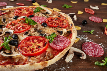 Closeup of pizza with salami, tomatoes and olives