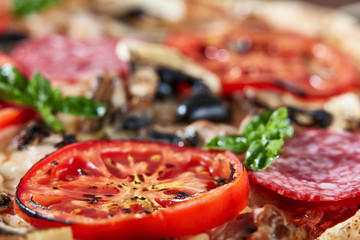 Closeup of pizza with salami, tomatoes and olives
