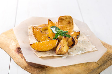 Fruits grilled with mint close up on a wooden board on the table.