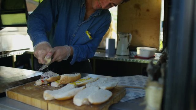  Street food vendor making hot dogs for customers at summer festival