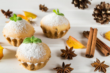 Obraz na płótnie Canvas Autumn pastries. Homemade cupcakes with powdered sugar with cinnamon sticks, anise stars and autumn leaves