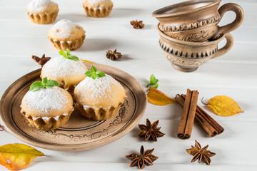 Autumn pastries. Homemade cupcakes with powdered sugar with cinnamon sticks, anise stars and autumn leaves