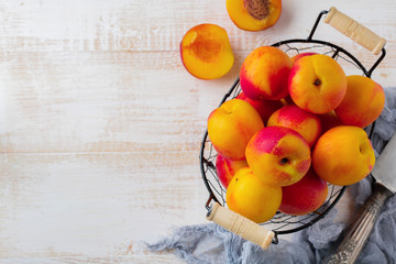 Fresh juicy fruit nectarines in metal grid on  white wooden background. Selective focus. Top view. Rustic style.