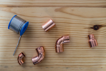 Tools on a wooden background for the installation of heating pipes, copper pipe parts and tile