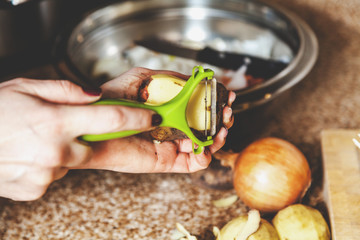Cleaning potatoes. Woman's hands clean potatoes special tool
