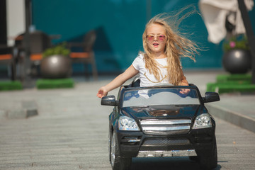 Little pretty girl driving a car. Child driving an automobile. Like a grown up