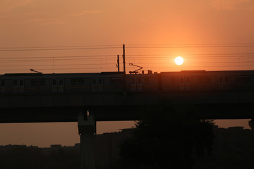 Fototapeta na wymiar Metro train entering in to the station during sunset silhouette.