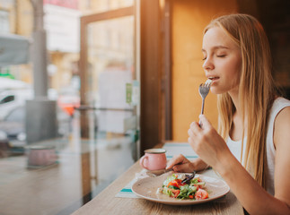 Portrait of attractive caucasian smiling woman eating salad