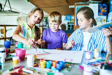 Naklejka premium Portrait of three children painting picture together smiling happily while working in art studio during lesson