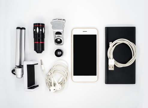 Flat lay (Top view) image of accessories (Tripod Phone Holder, Universal Clamp Camera Lens, Earphone, Power Bank, USB Charger Cable) around smartphone on white background